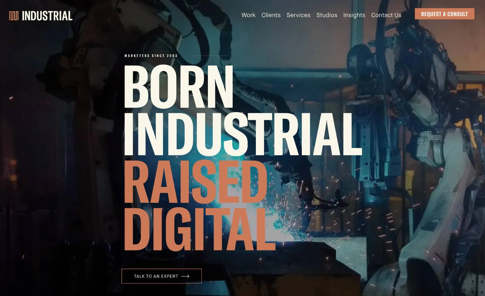 INDUSTRIAL agency homepage with the bold tagline “Born Industrial, Raised Digital” over a background of robotic arms welding in a dimly lit factory.
