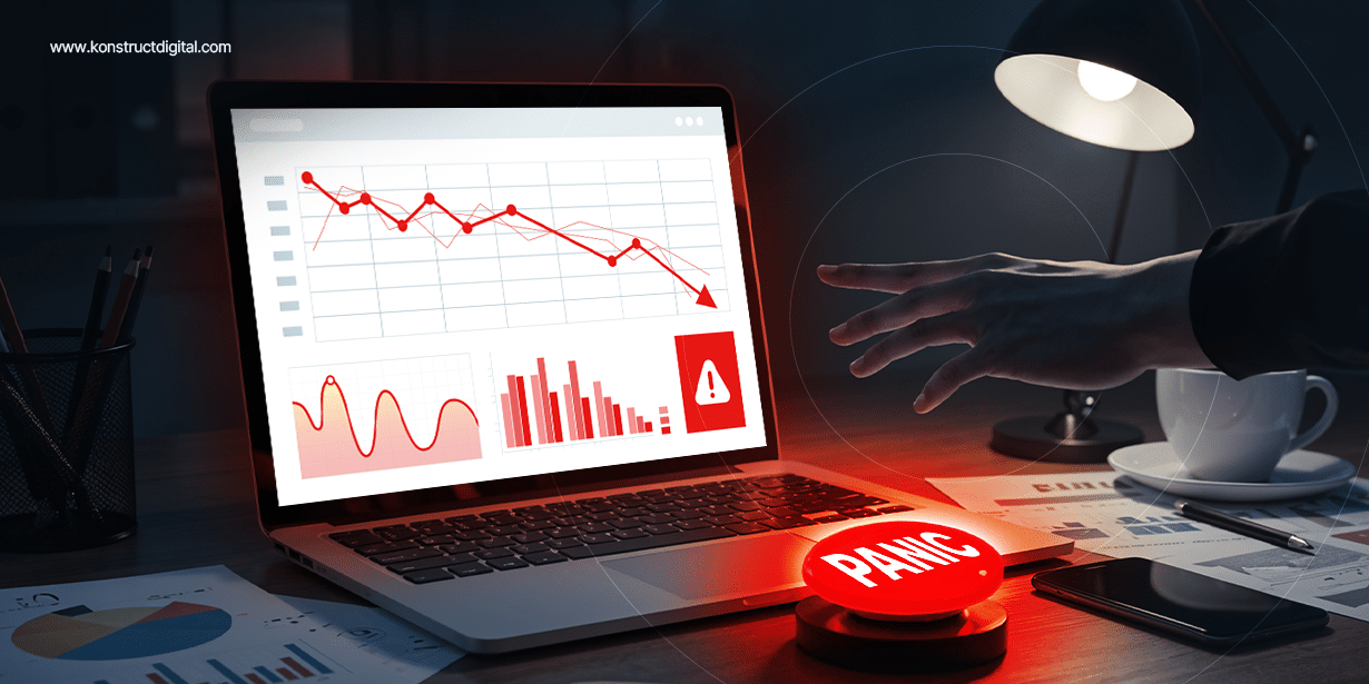Person reaching toward a red panic button on a desk, with a laptop displaying declining marketing metrics and warning symbols, indicating a drop in B2B performance.