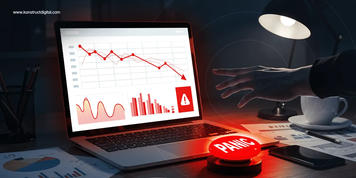 Person reaching toward a red panic button on a desk, with a laptop displaying declining marketing metrics and warning symbols, indicating a drop in B2B performance.