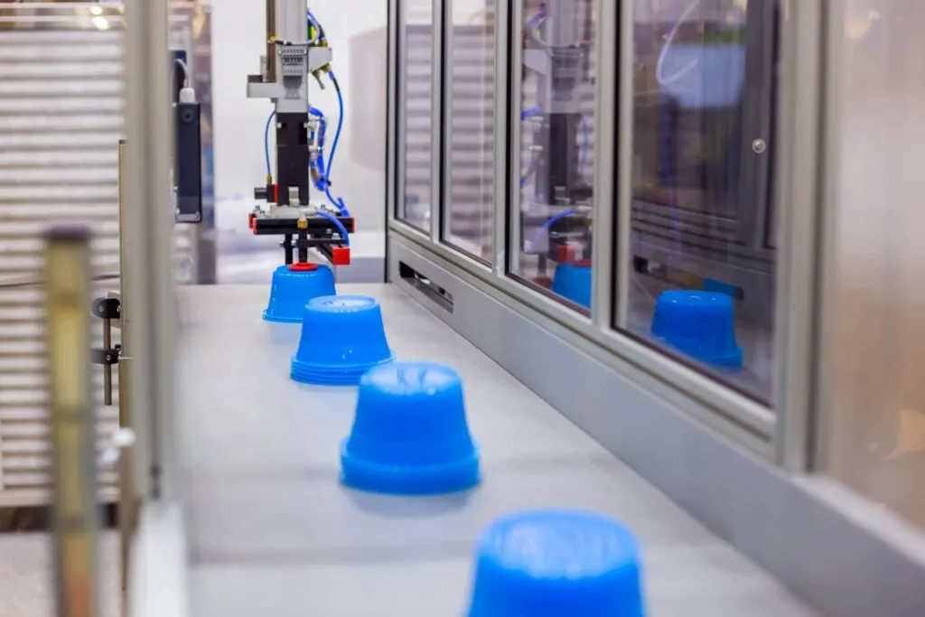 Robotic system removing blue plastic parts from the injection molding machine on the conveyor line