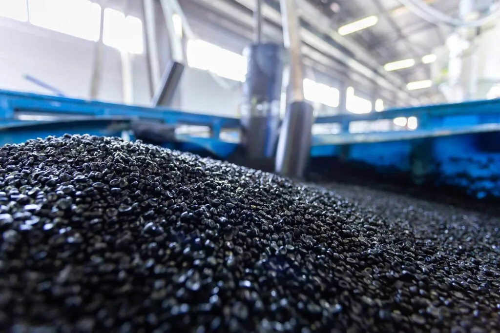 Close-up of black plastic pellets used in injection molding at a manufacturing facility